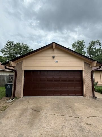 A brown garage door is sitting in front of a house.
