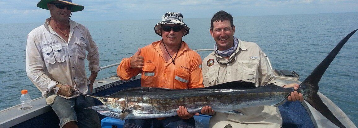 Three men carrying big fish — Barramundi Fishing Darwin in Winnellie, NT