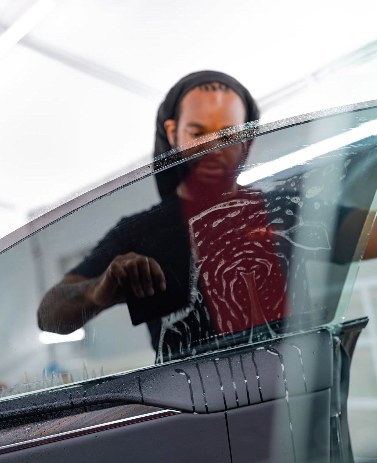 A man is applying window tinting to a car window.