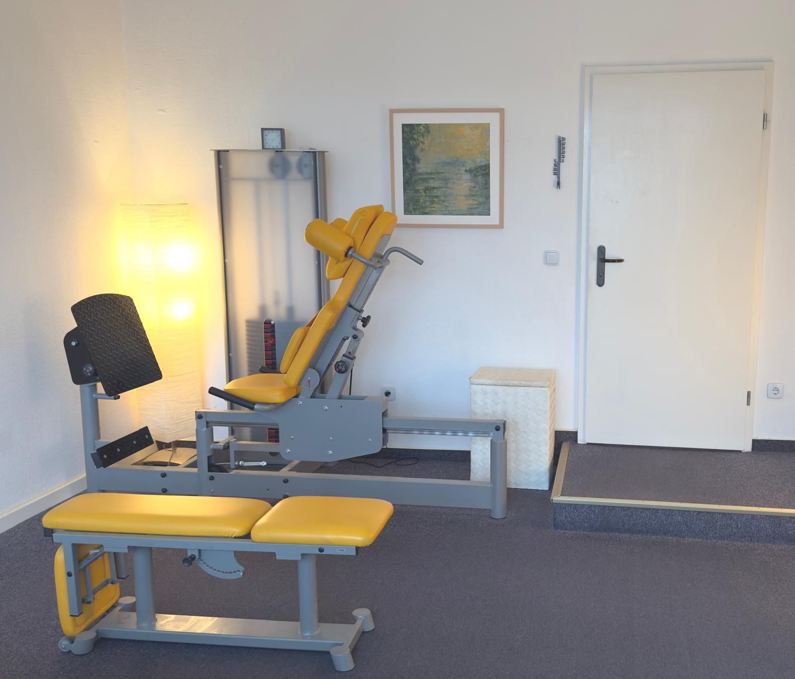 Ein Fitnessraum mit einer gelben Bank und einer gelben Beinpresse in der Privatpraxis von Roland Hauf