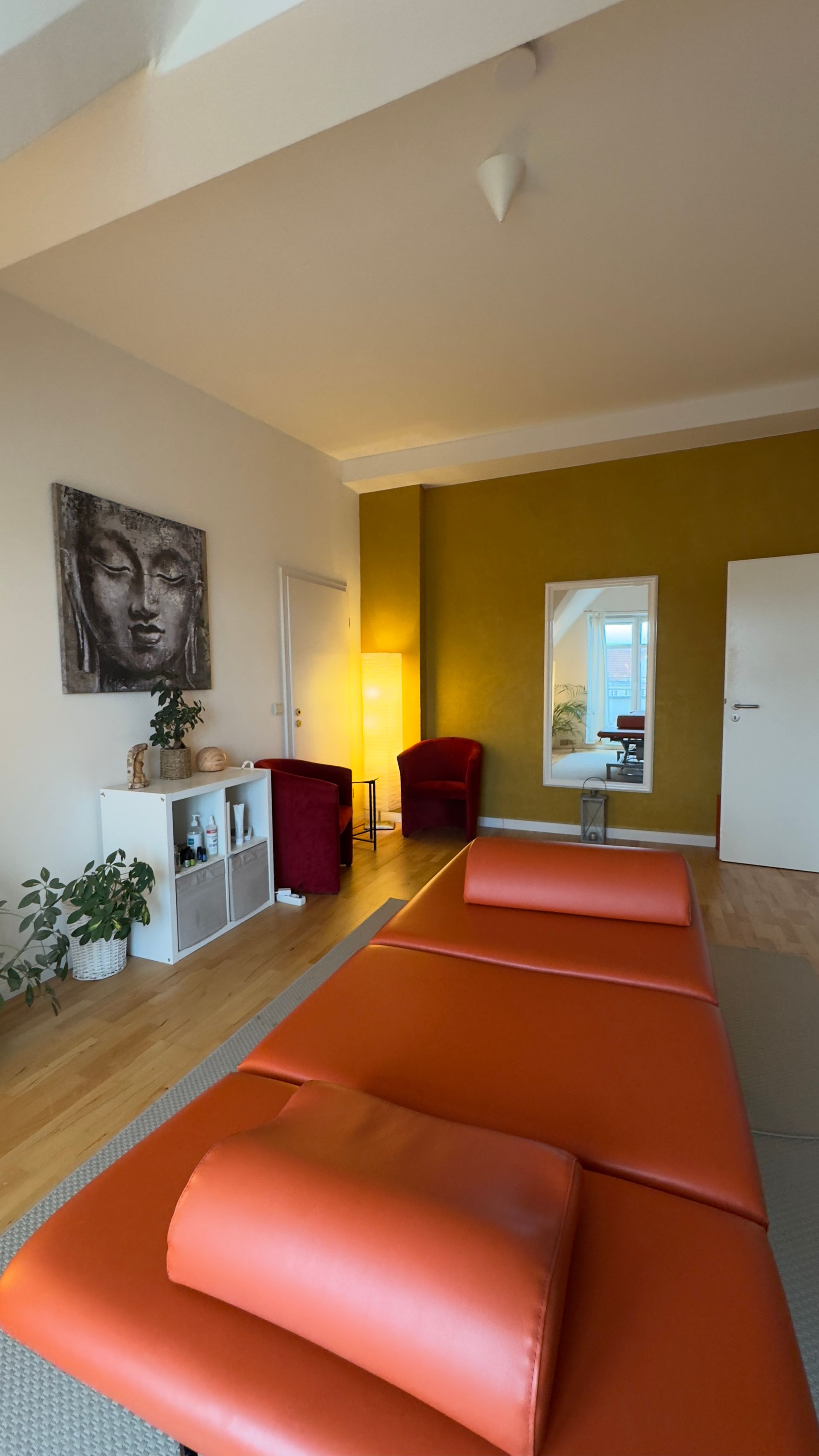 Ein Zimmer mit einer Massageliege und einem Spiegel an der Wand in der Privatpraxis von Roland Hauf