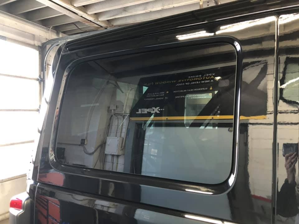 A black van with a large window is parked in a garage.
