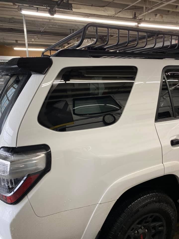A white suv with a roof rack is parked in a garage.