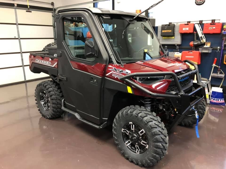 A red atv is parked in a garage next to a garage door.