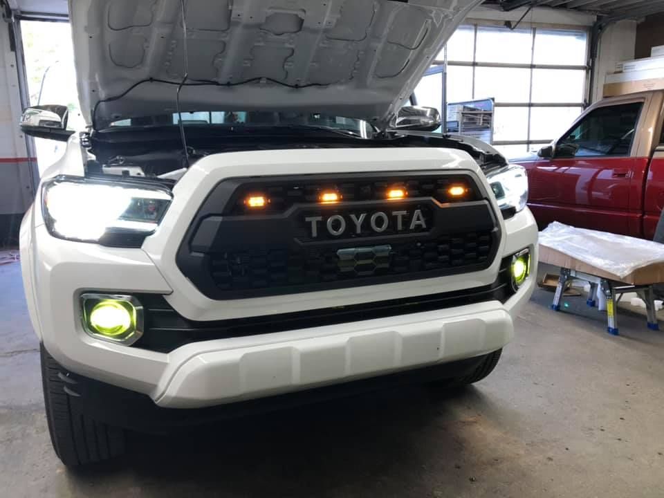 A white toyota tacoma with the hood up in a garage
