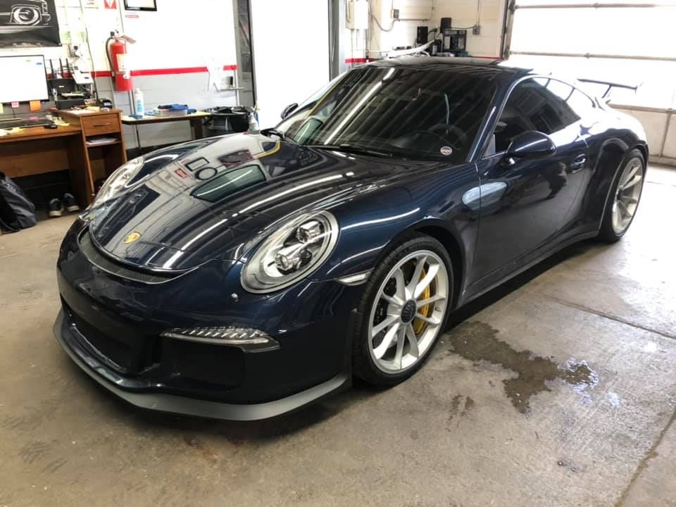 A blue porsche 911 is parked in a garage.