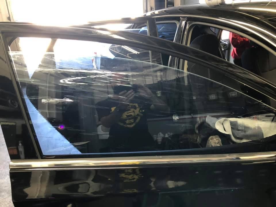 A man is taking a picture of himself in a car window.