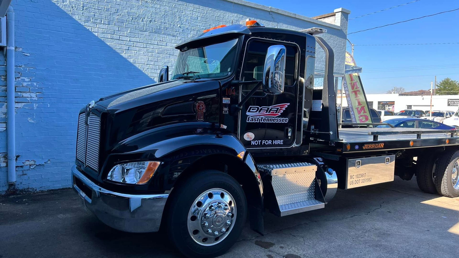 A black tow truck is parked in front of a building.