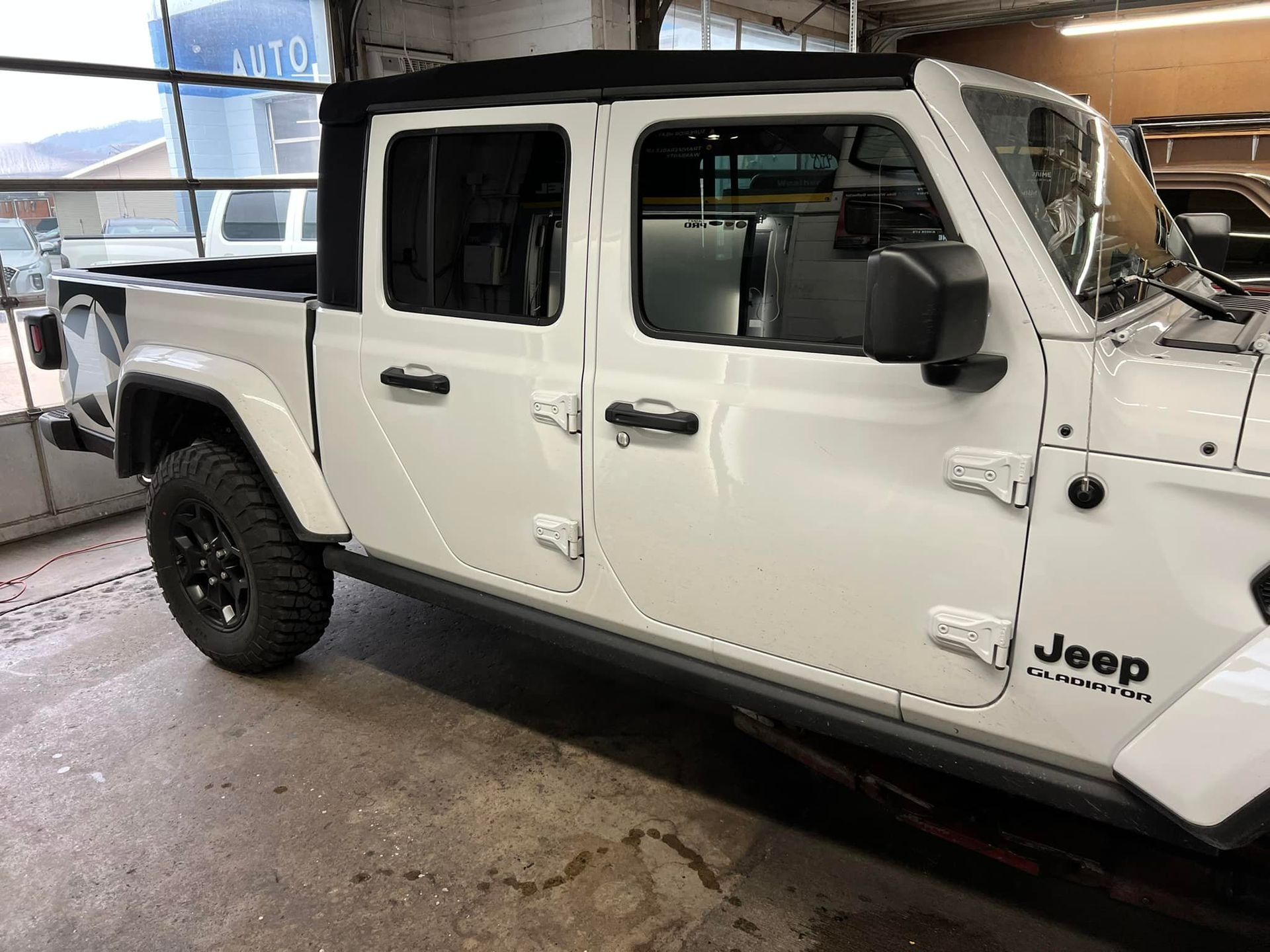 A white jeep is parked in a garage.