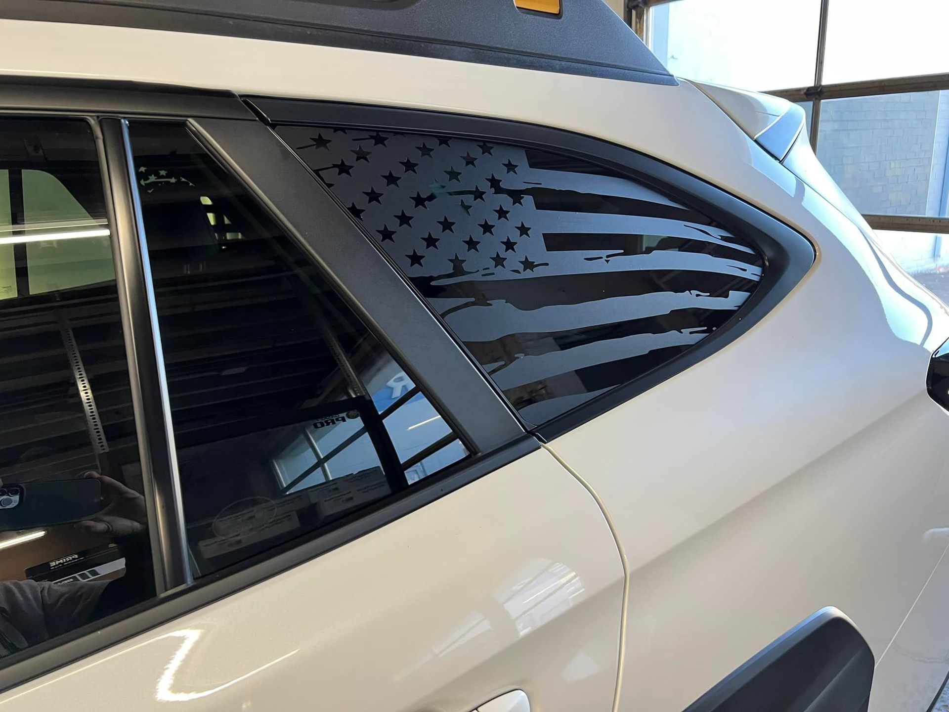 A white car with an american flag on the side window