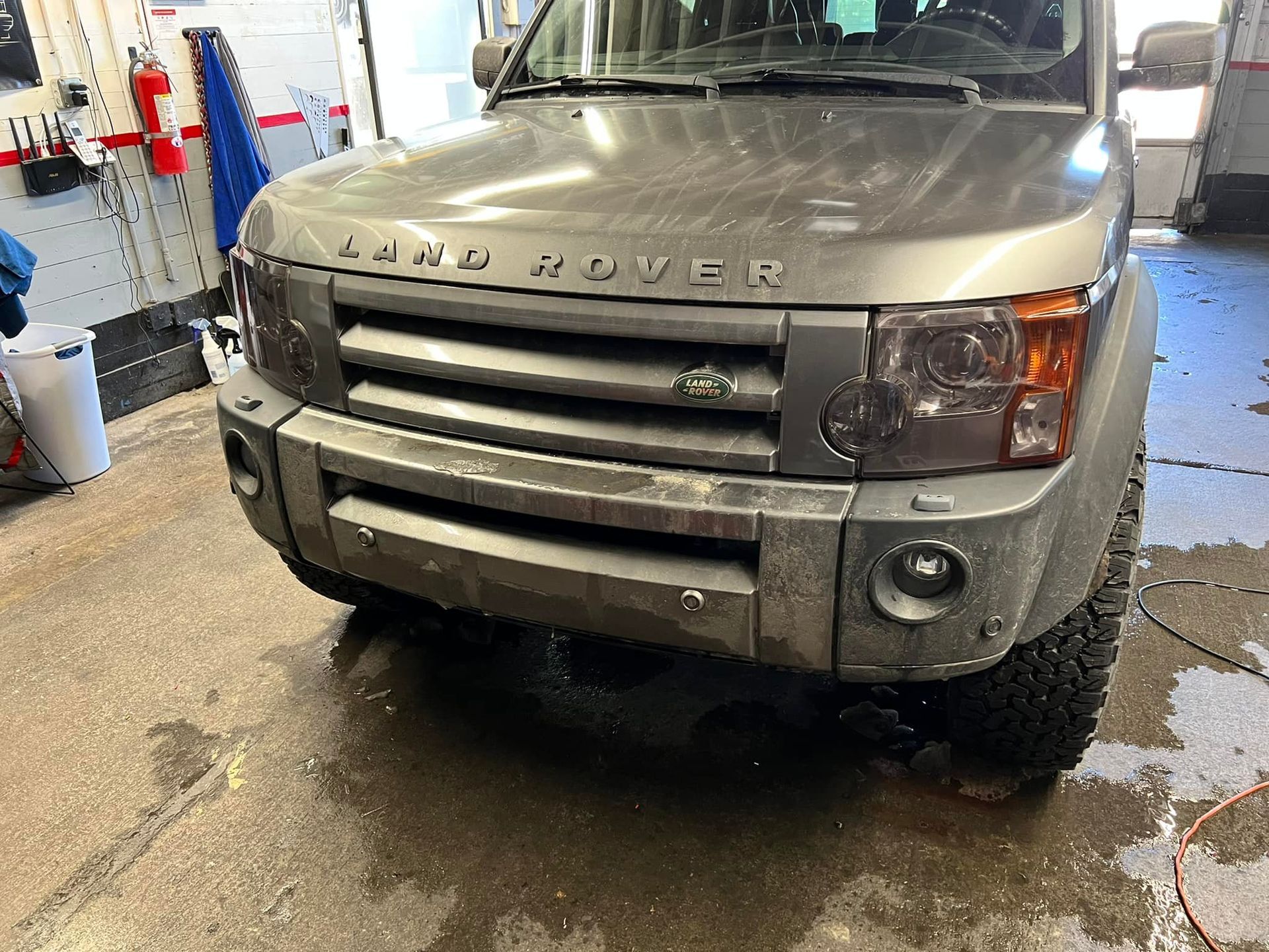 A gray land rover is parked in a garage.