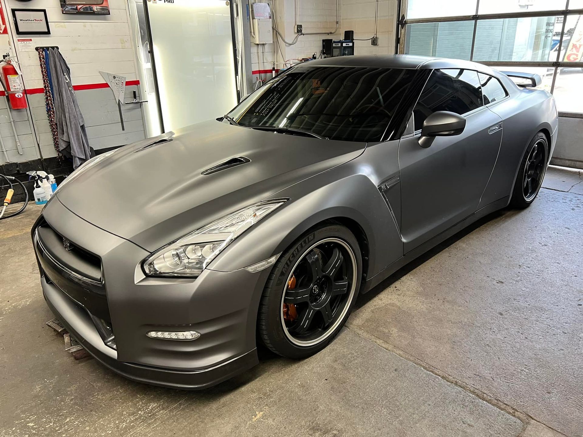 A gray sports car is parked in a garage.