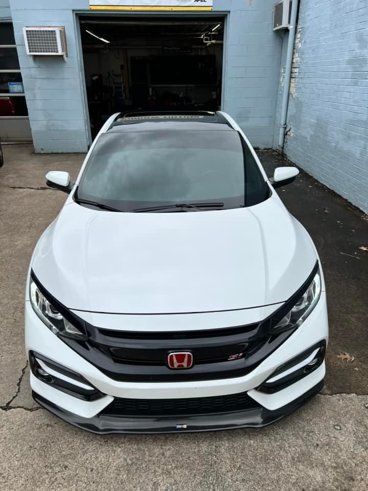 A white honda civic is parked in front of a garage.