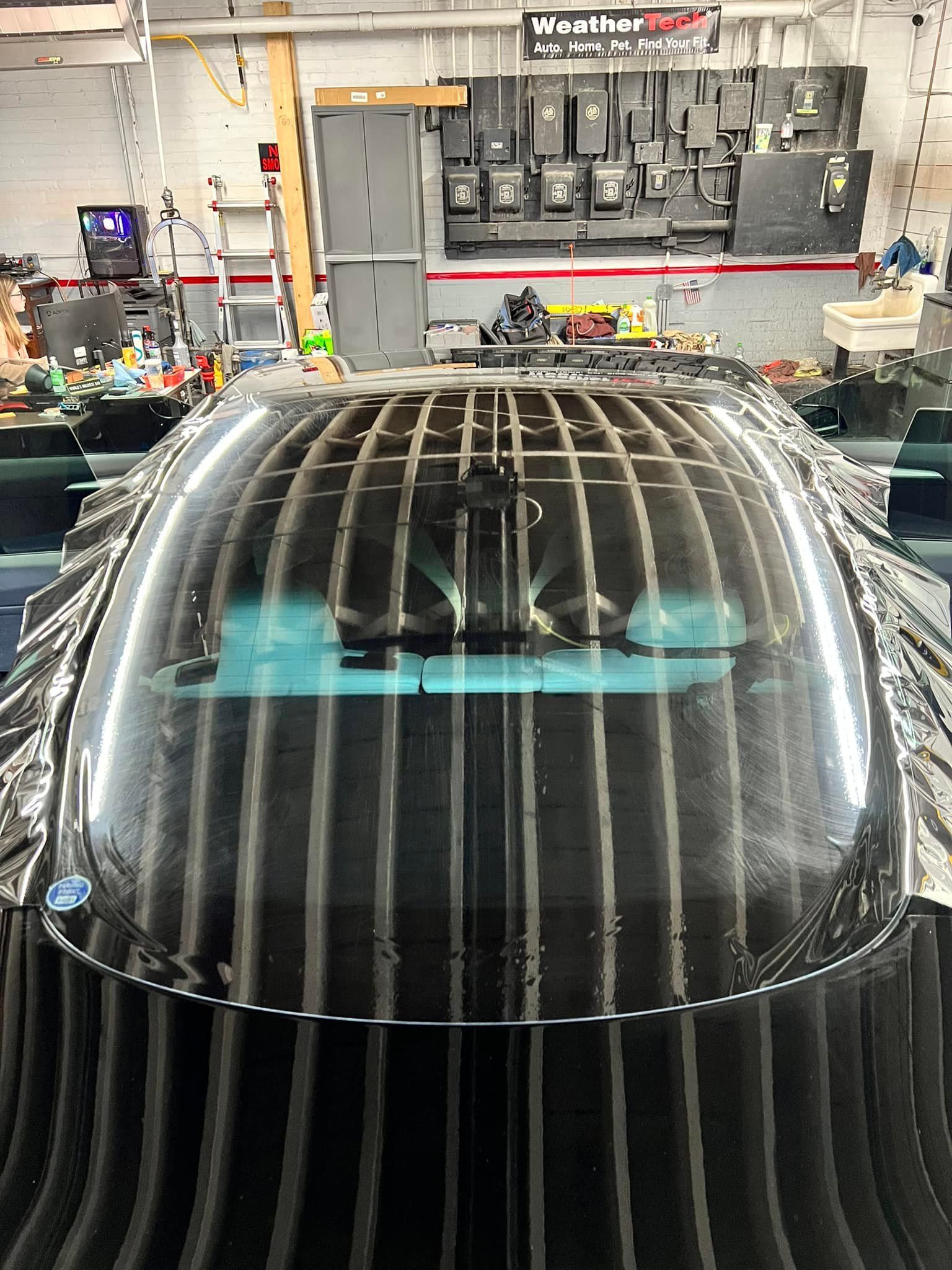 A black car is parked in a garage with a clear roof.