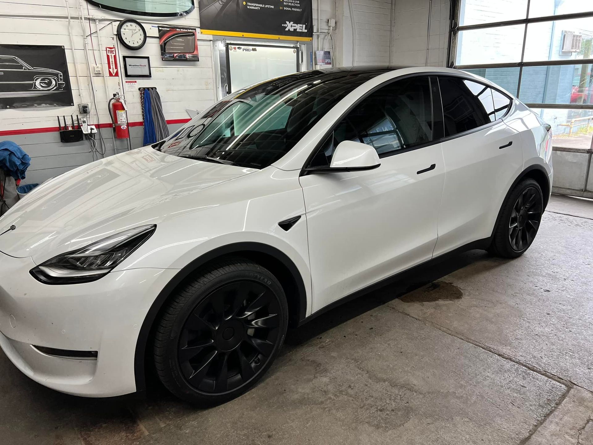 A white tesla model y is parked in a garage.