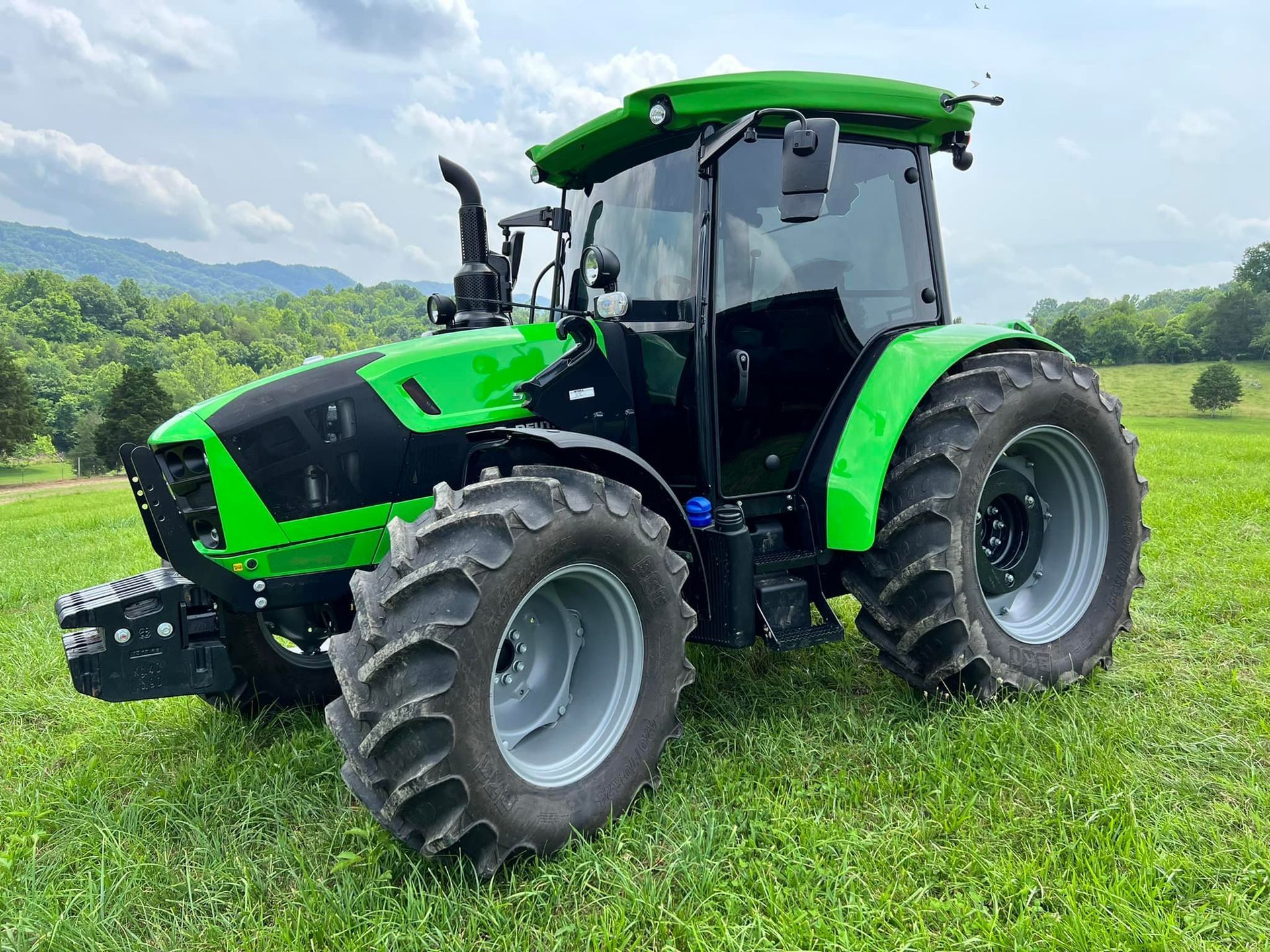 A green tractor is parked in a grassy field.