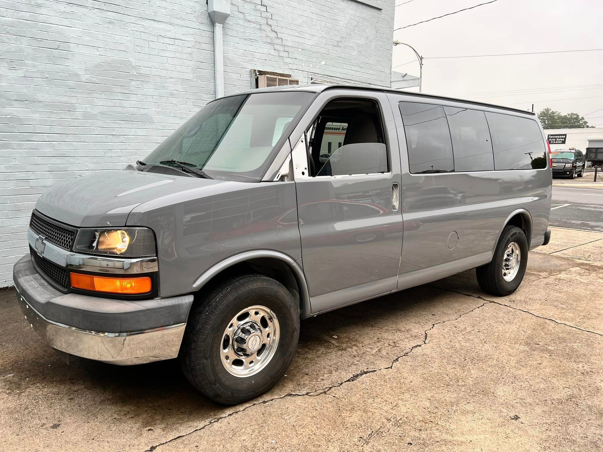 A gray van is parked in front of a building.