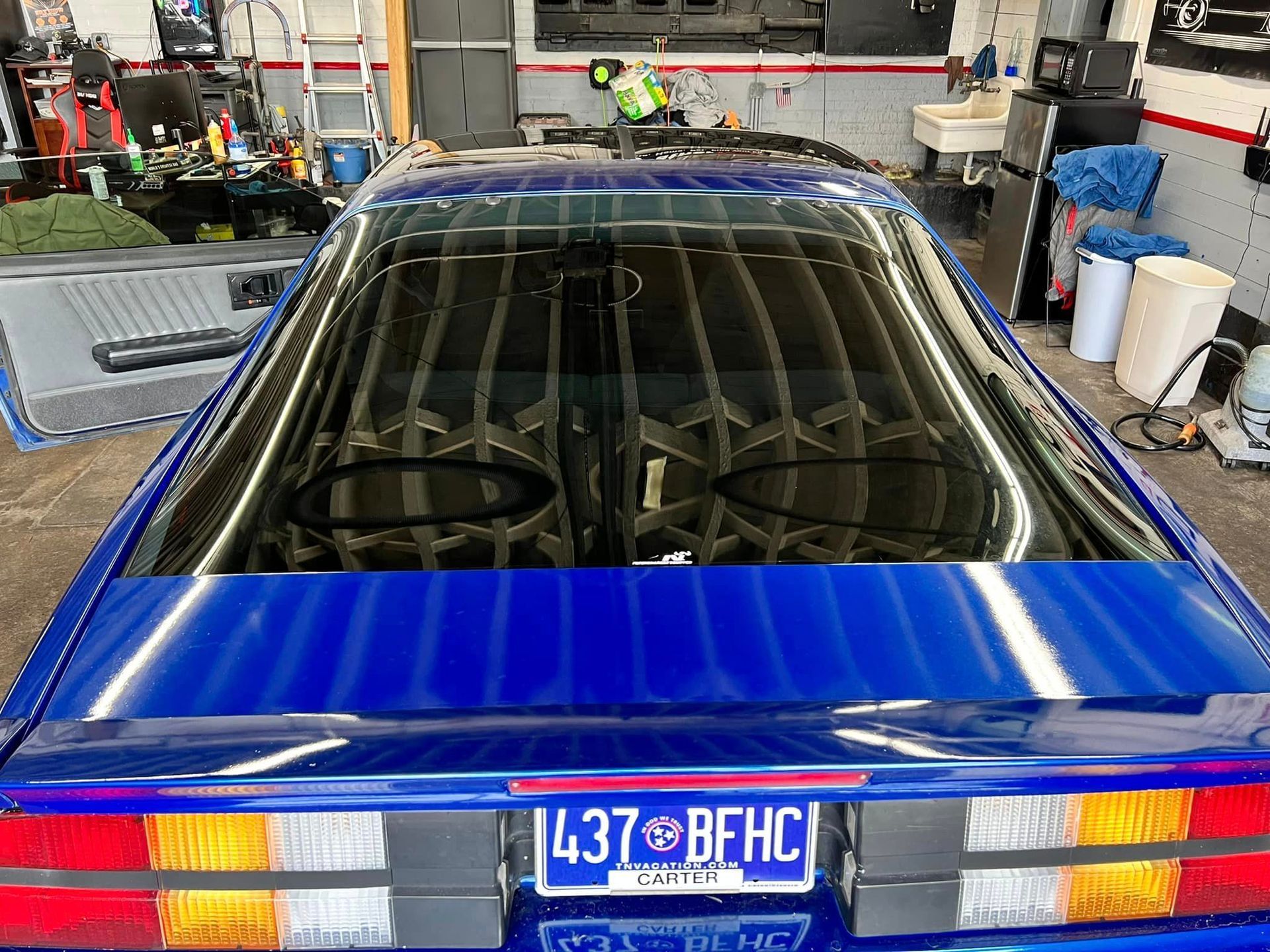 A blue car with a license plate that says 437 bfhc is parked in a garage.