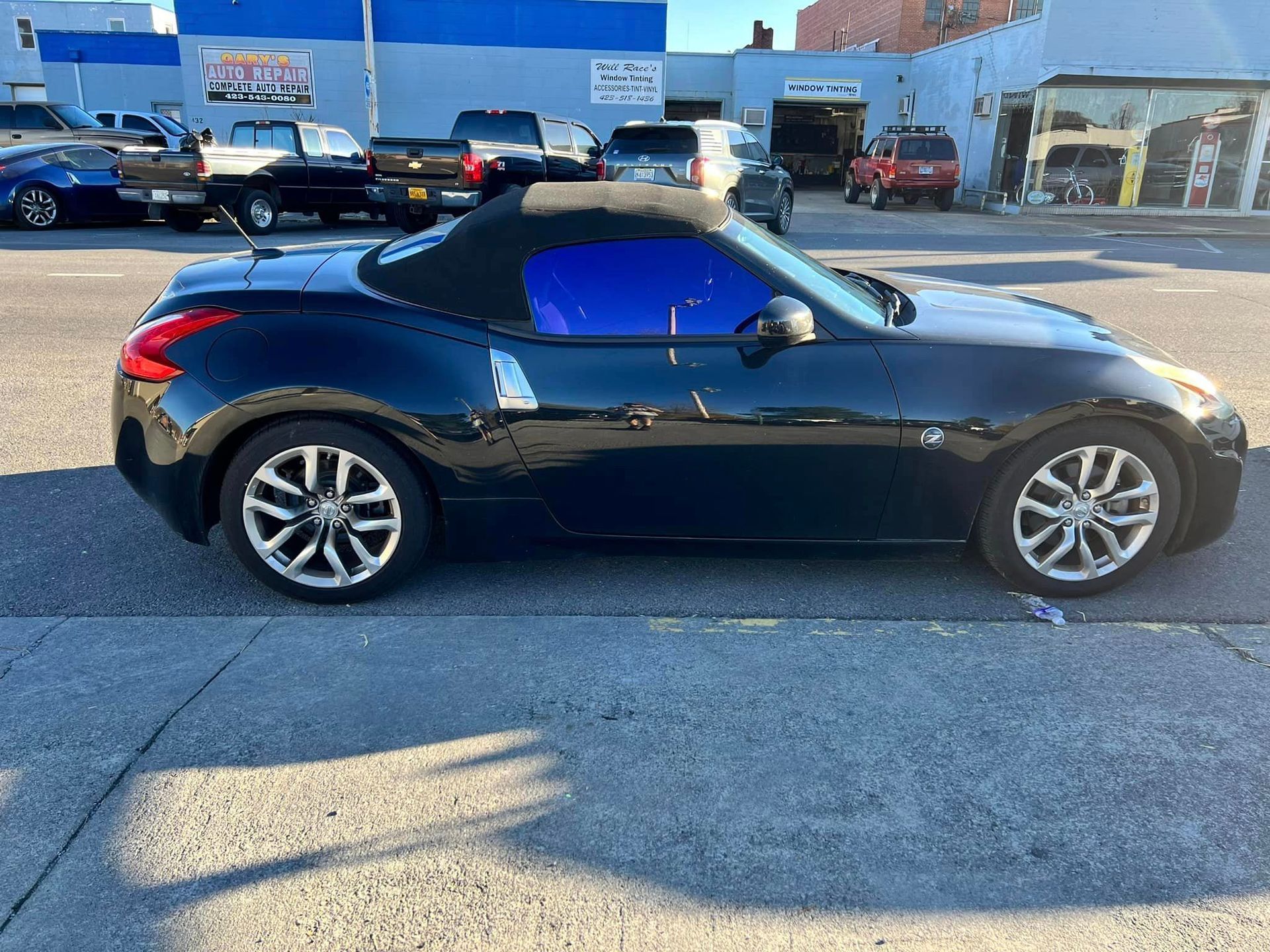 A black convertible sports car is parked on the side of the road