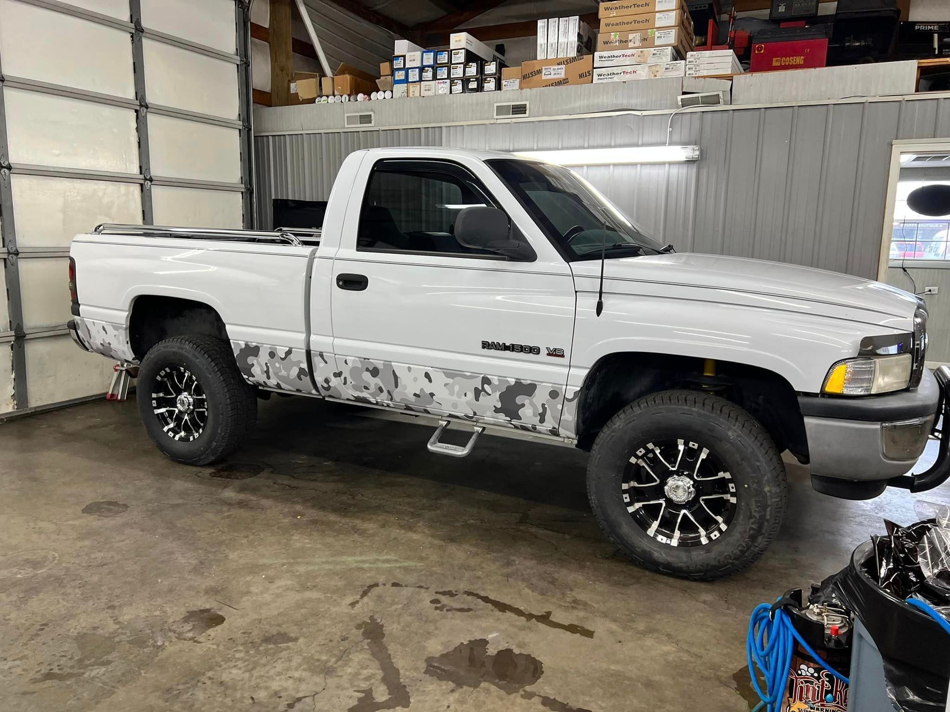 A white truck is parked in a garage next to a garage door.