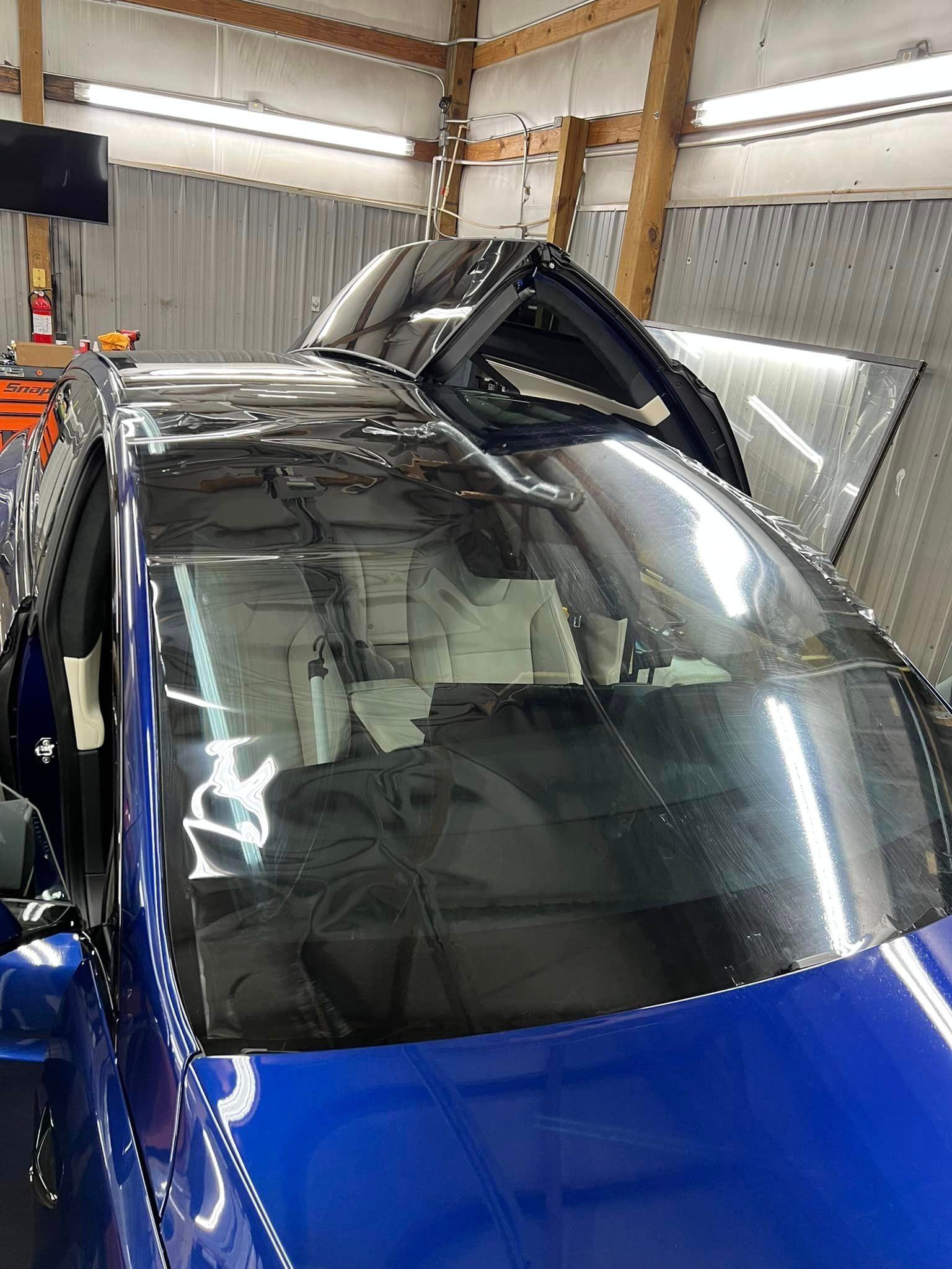 A blue truck with a black roof is parked in a garage.