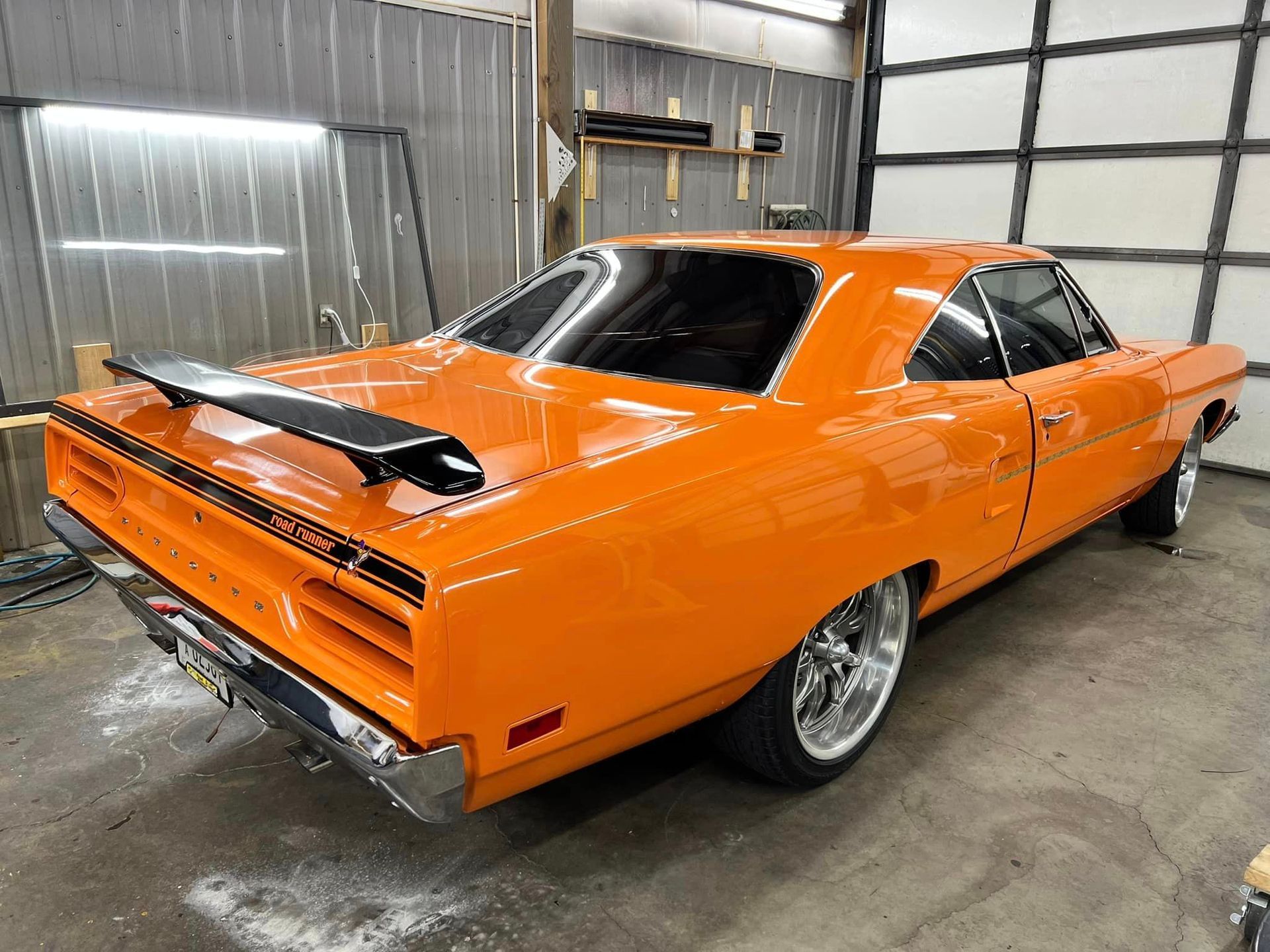 An orange muscle car is parked in a garage