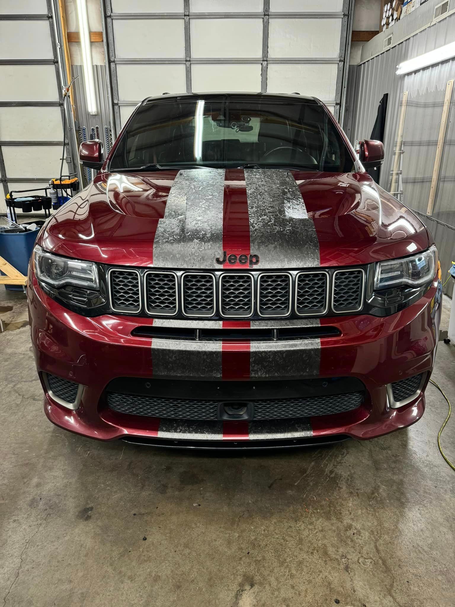 A red jeep grand cherokee is parked in a garage.