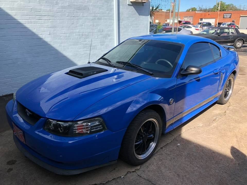 A blue mustang is parked in front of a building.