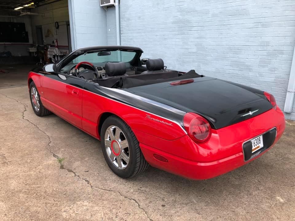 A red convertible is parked in front of a brick building.