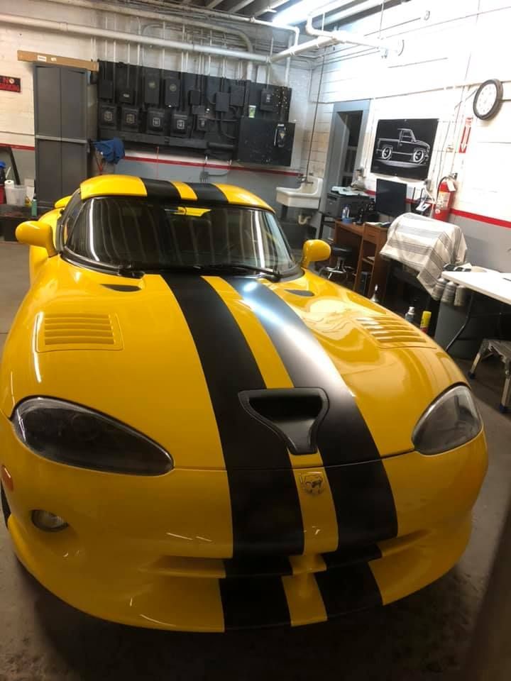 A yellow sports car with black stripes is parked in a garage.
