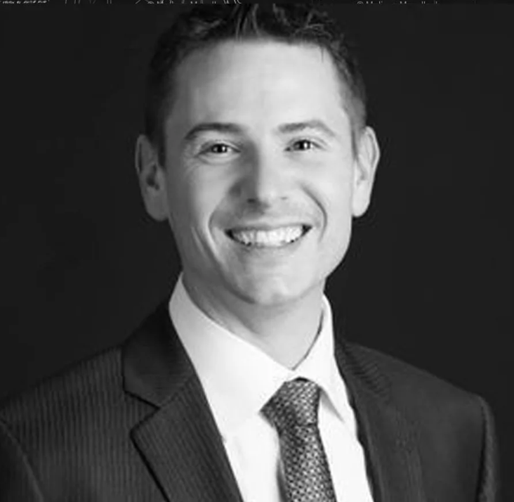 A man in a suit and tie is smiling in a black and white photo.