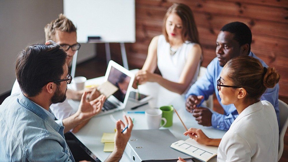 A group of people are sitting around a table having a meeting.