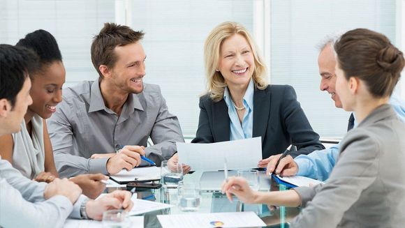 A group of people are sitting around a table having a meeting.