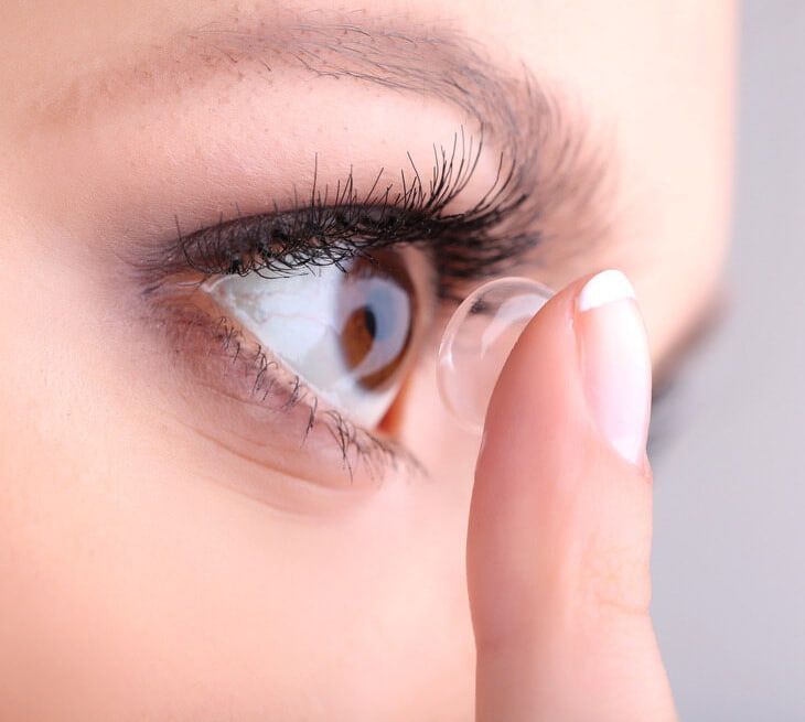 A Woman is Putting a Contact Lens in Her Eye — Ian Emslie Optometrist In Warners Bay, NSW