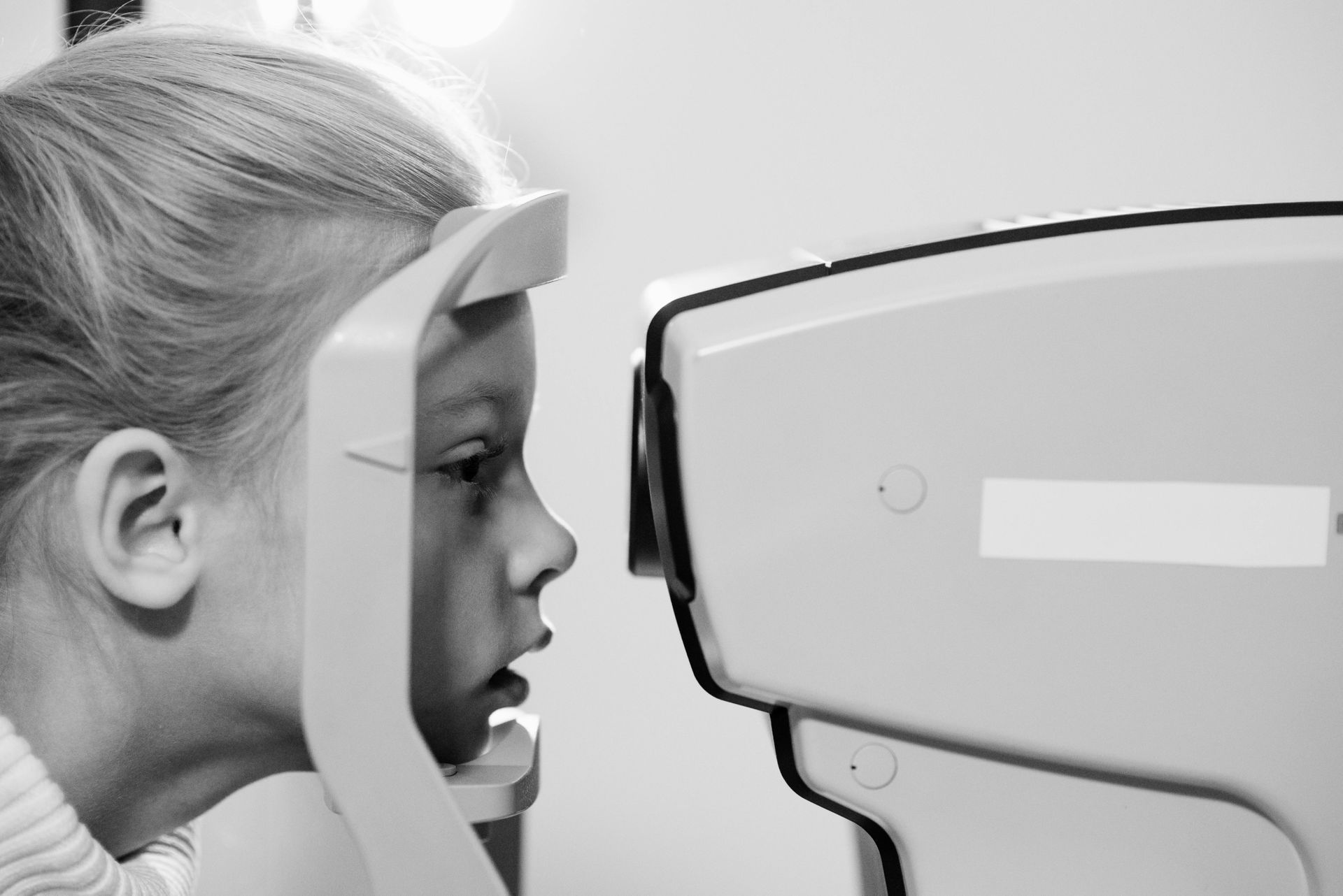 A little girl is getting her eyes checked by a machine — Ian Emslie Optometrist In Warners Bay, NSW