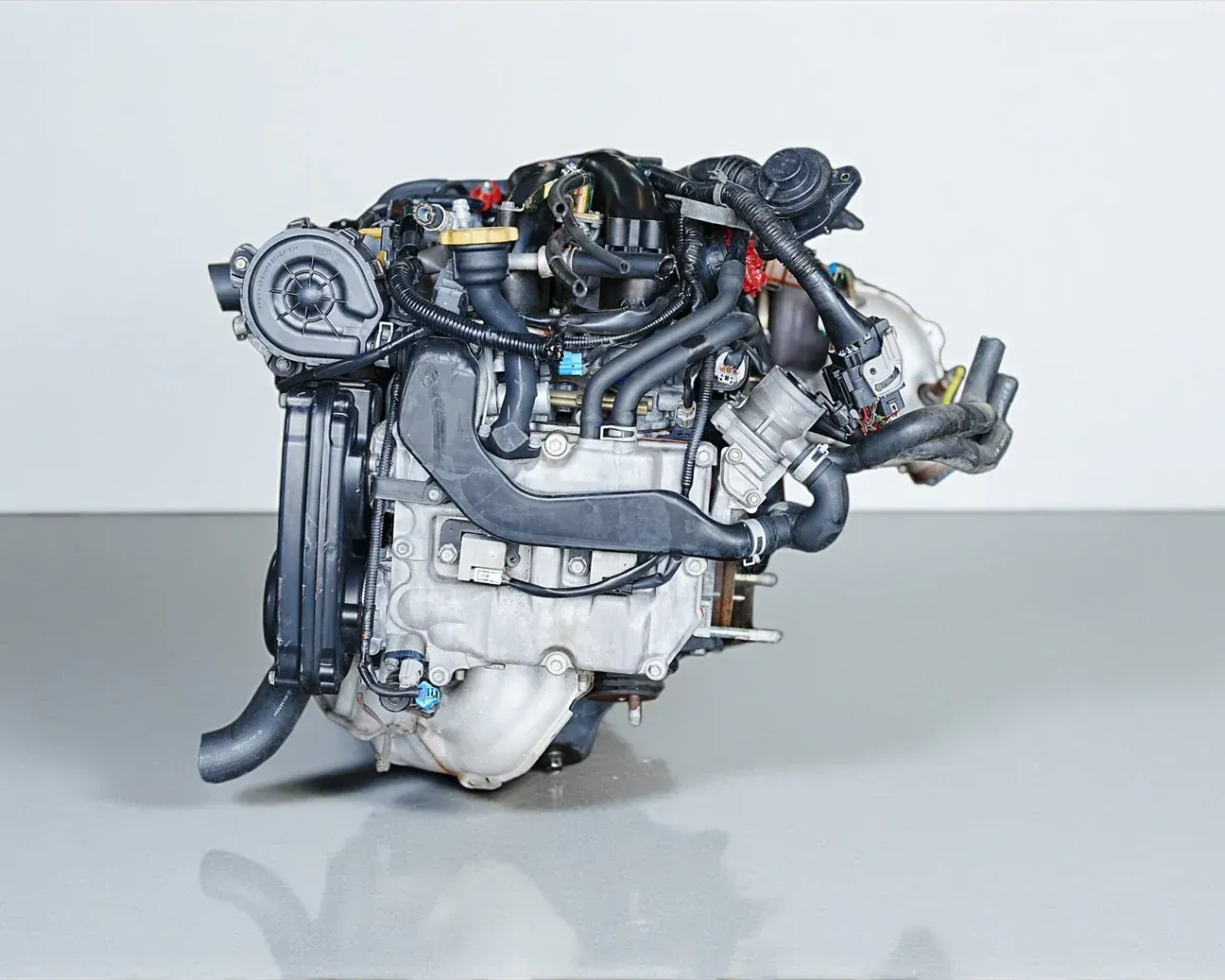 A complex, metallic automotive internal combustion engine assembly viewed against a plain white background.
