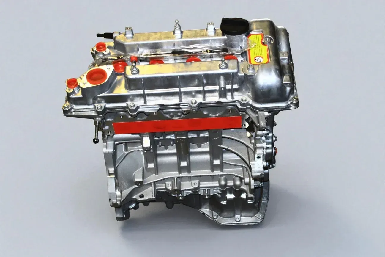 A clean, metallic car engine block showing the cylinder head and engine casing against a light gray background.