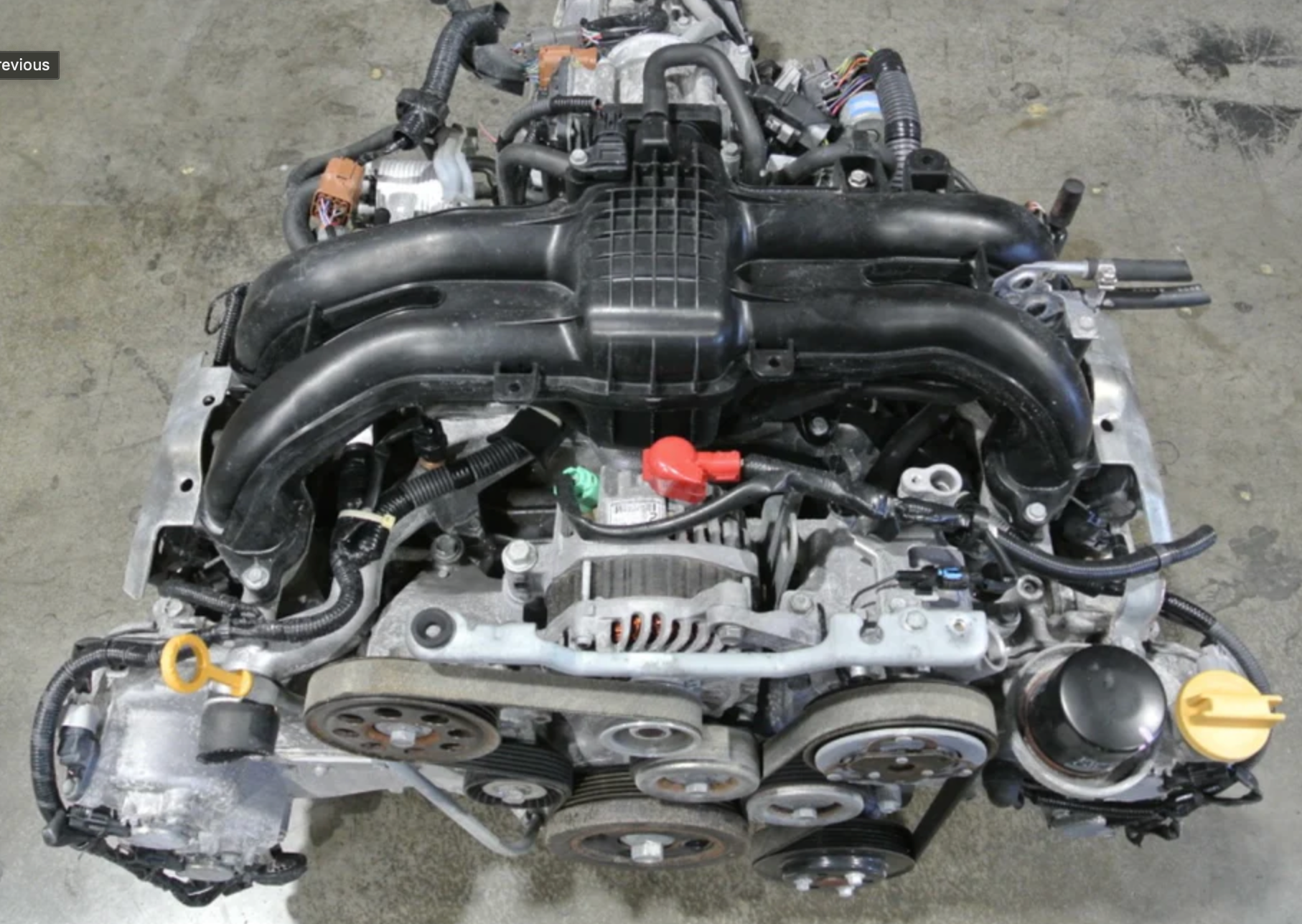 A complete Subaru boxer engine shown from the top-front angle, featuring a black intake manifold and serpentine belt.