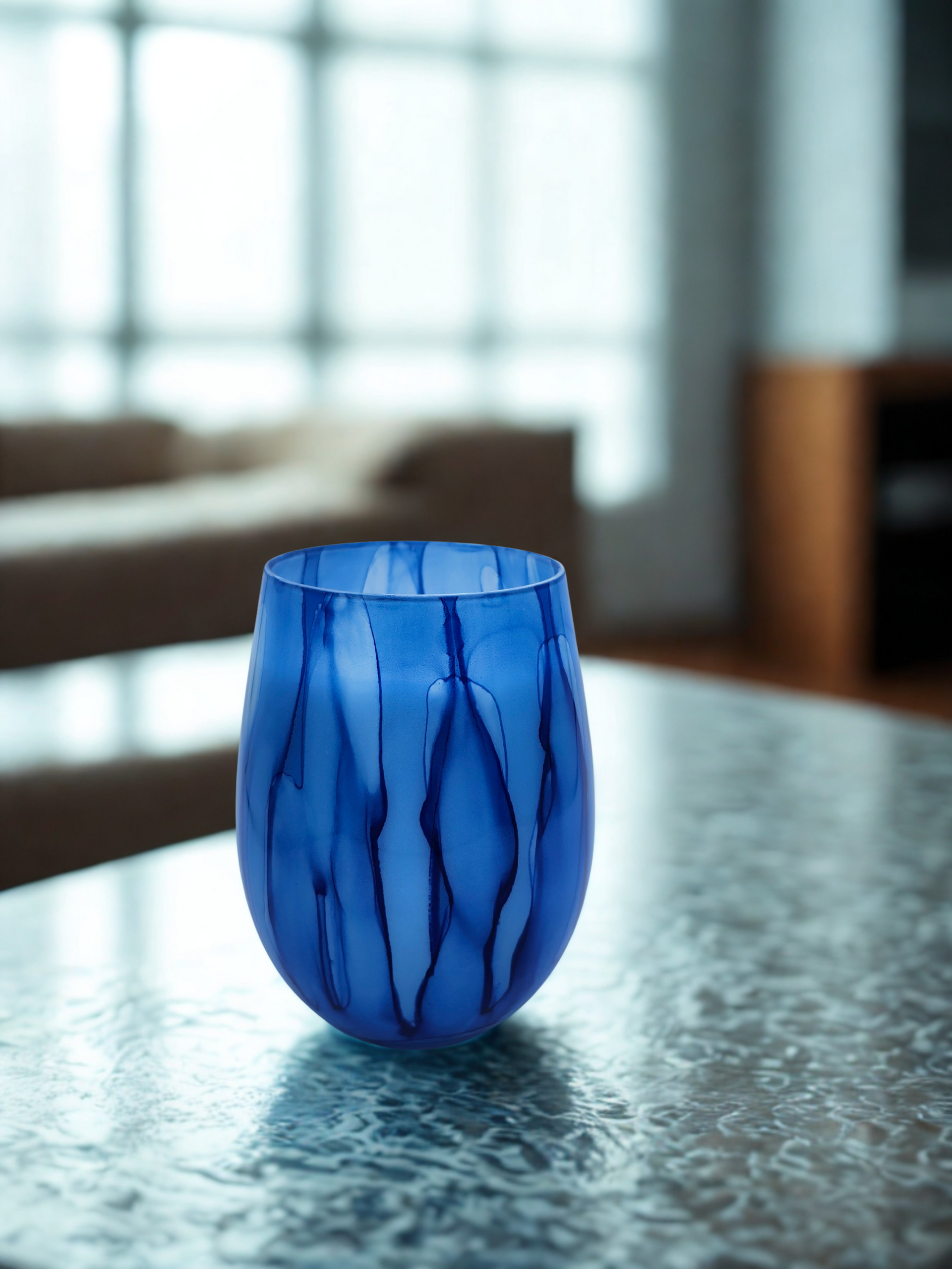 Blue glass vase on a textured table, with a blurred living room background.