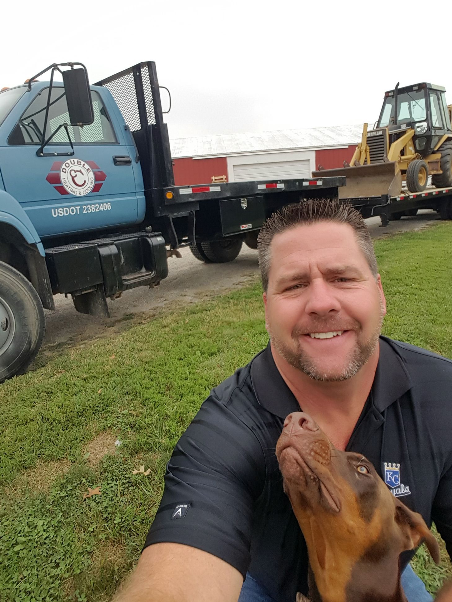 A man is taking a selfie with his dog in front of a tow truck.