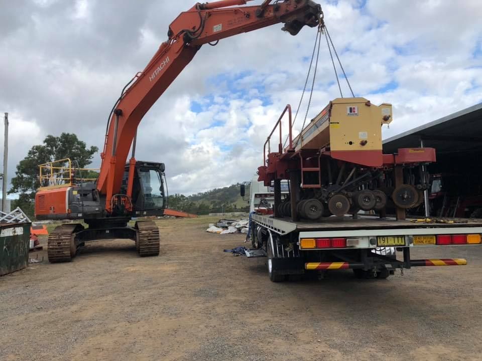 A crane is lifting a machine on a flatbed truck