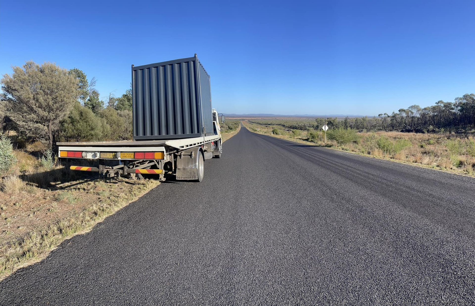 A truck with a container on the back is driving down a road.