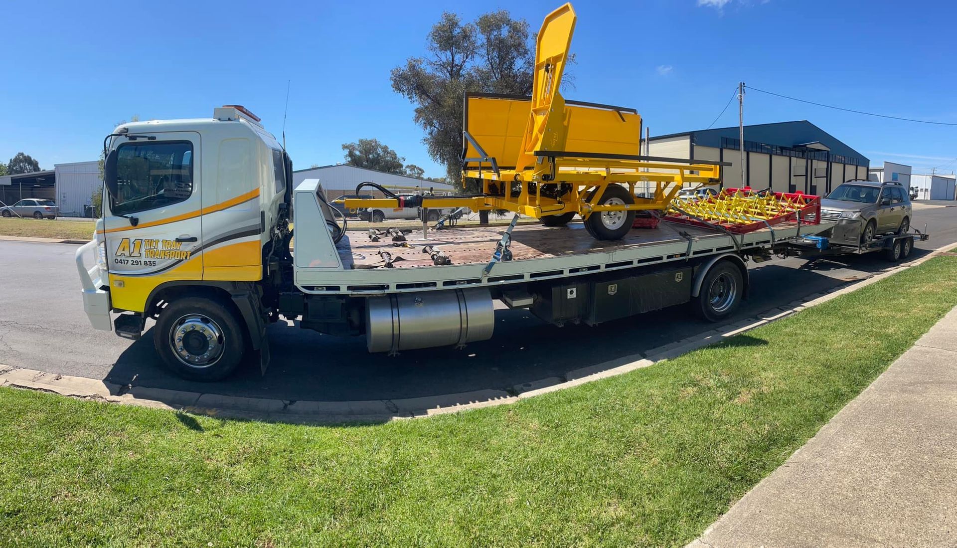 A tow truck is carrying a yellow vehicle on a trailer.