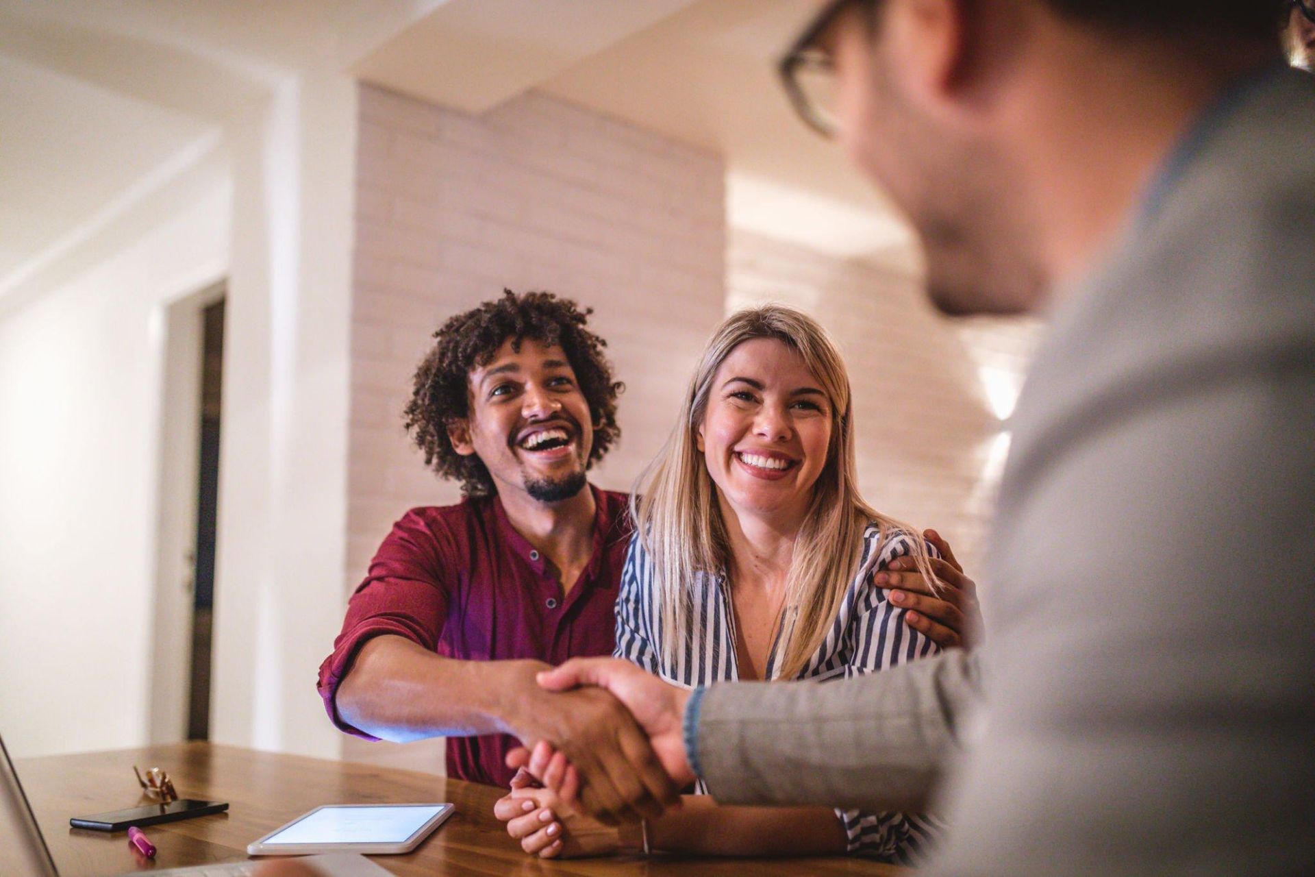 A man and a woman are shaking hands with a real estate agent.