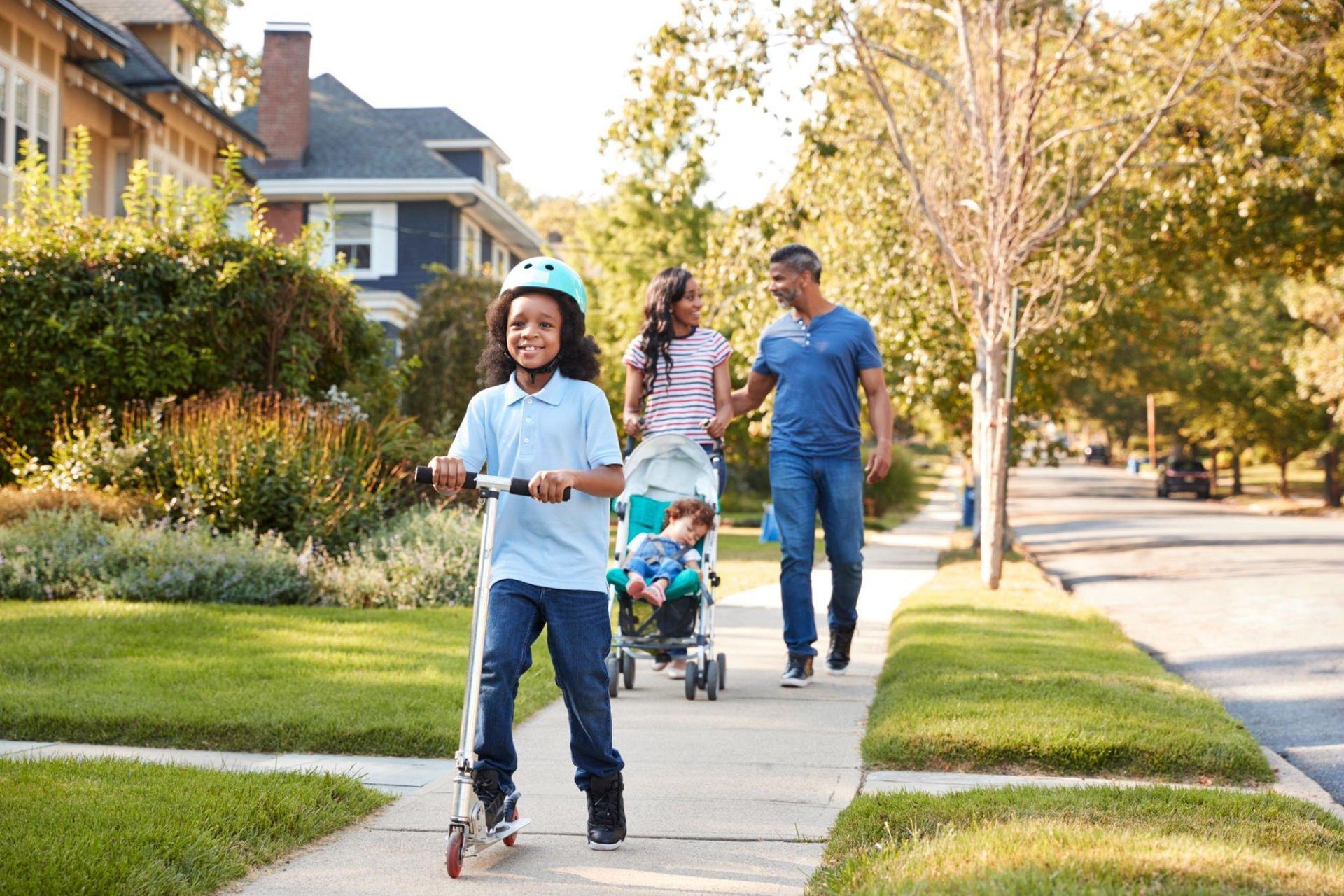 A family is walking down the sidewalk in a residential neighborhood.