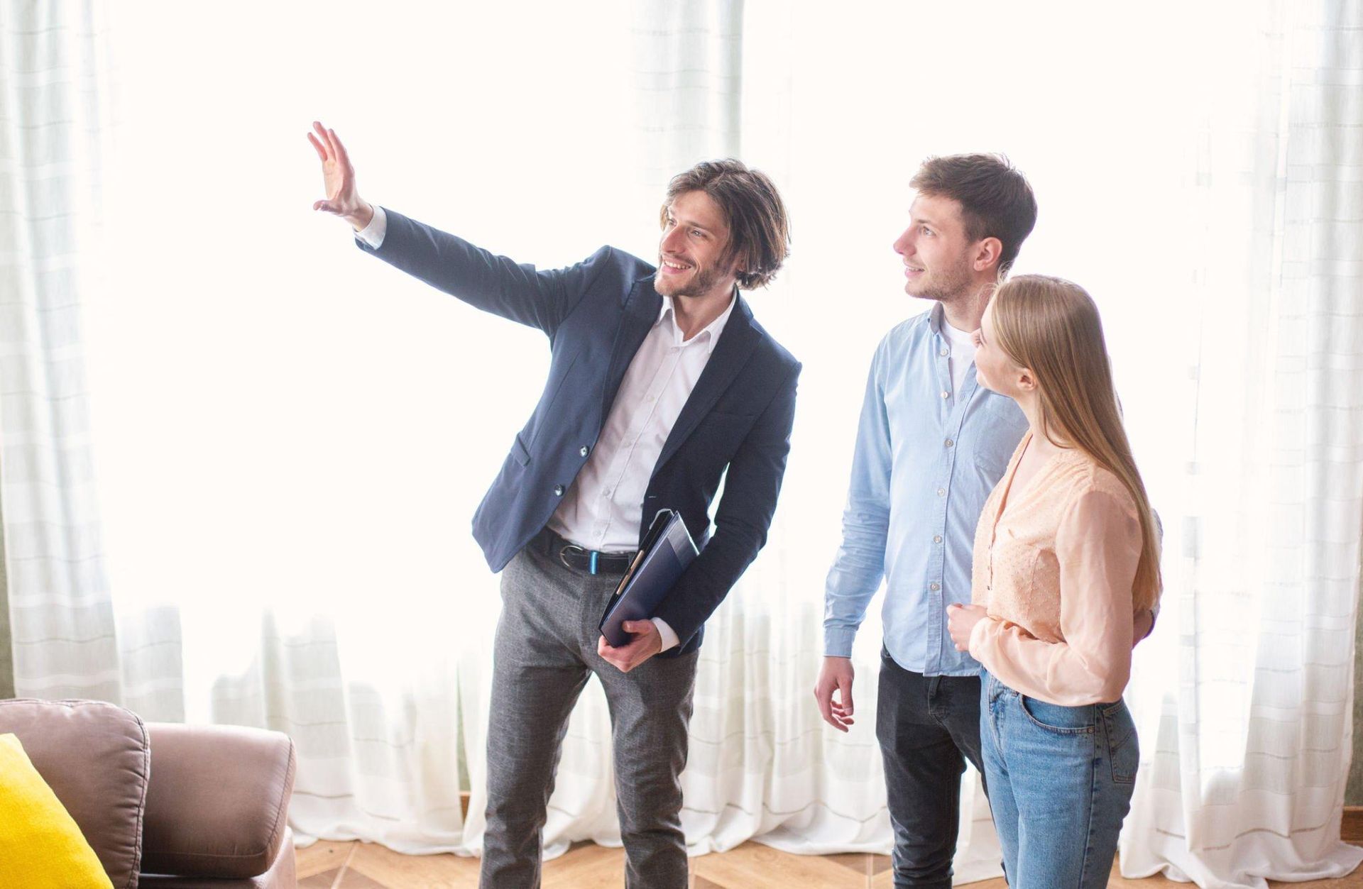 A man is standing next to a woman and a man in a living room.