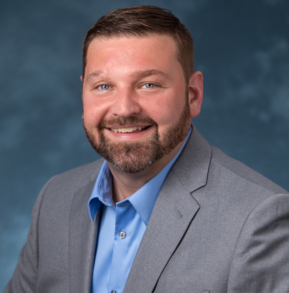 A man in a suit and blue shirt is smiling for the camera.