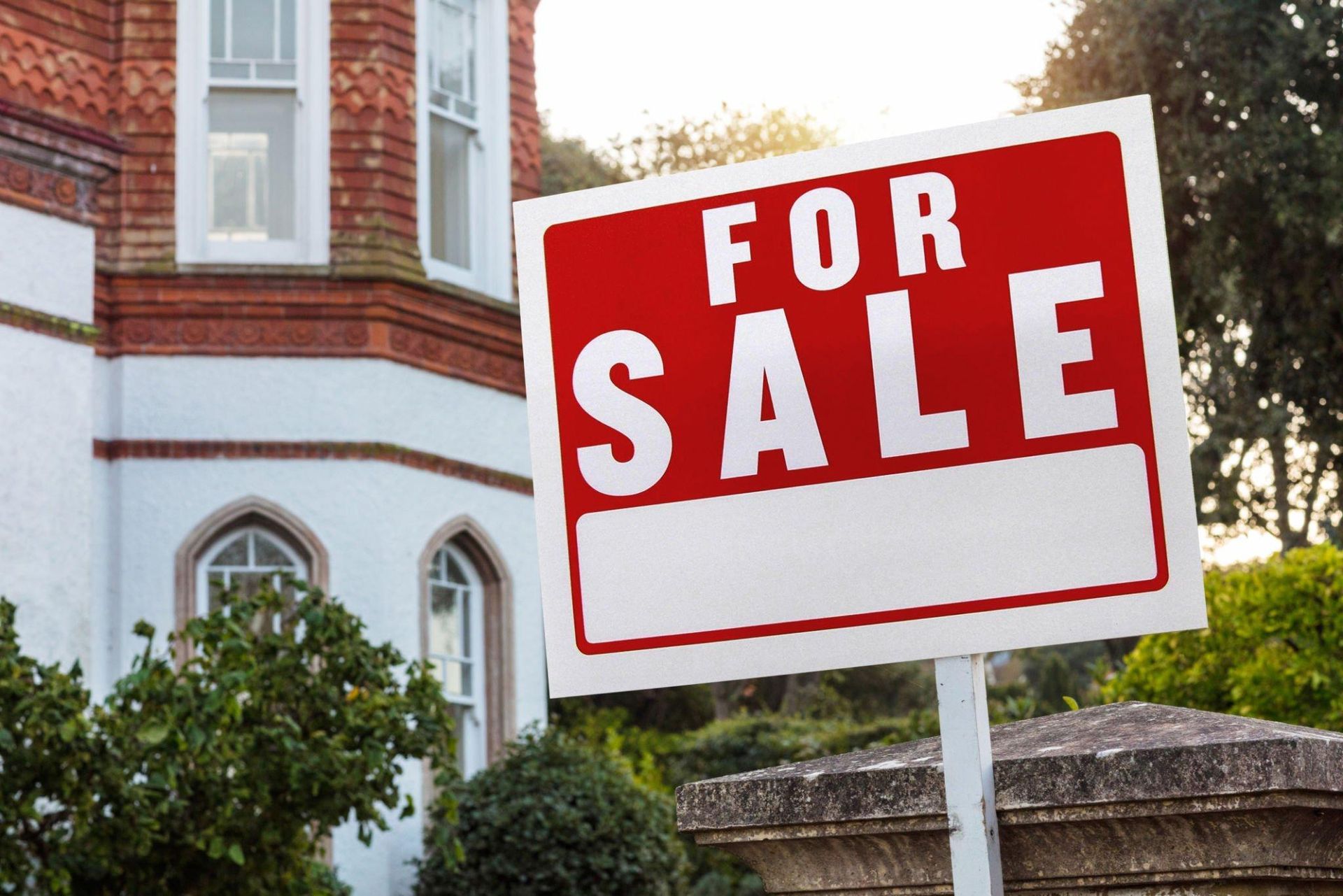 A red and white for sale sign in front of a house