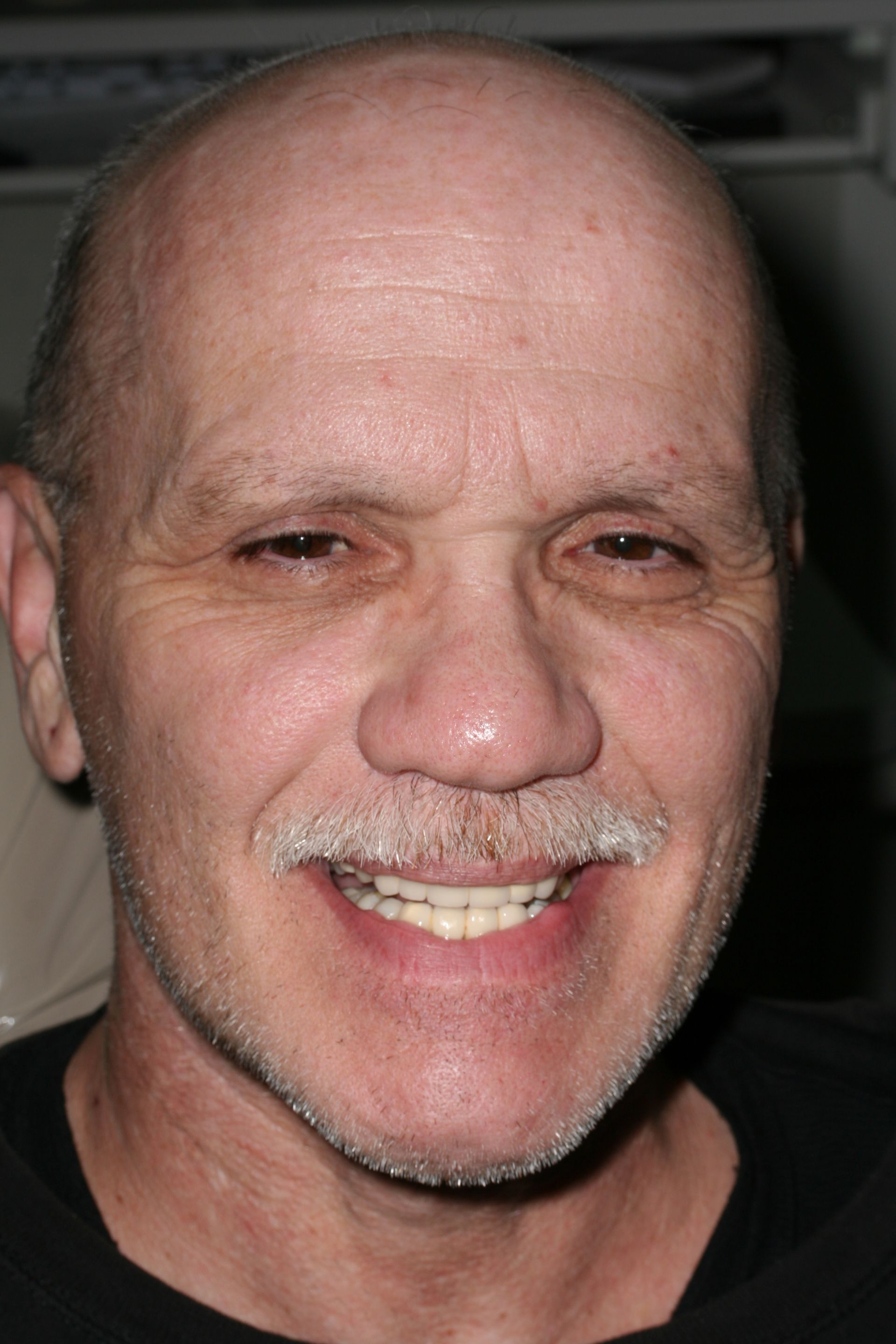 A bald man with a beard and mustache is smiling for the camera.