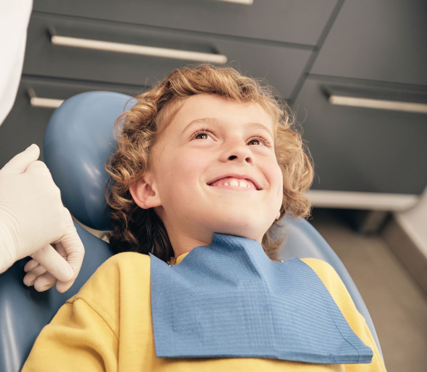 A young boy is smiling while sitting in a dental chair